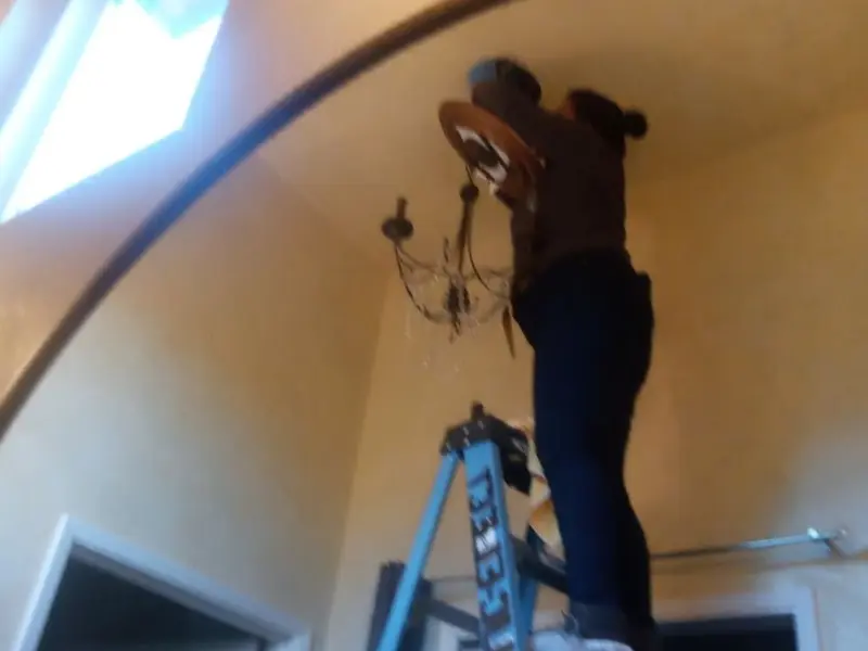 Electrician installing a chandelier in a Fleming Island residence